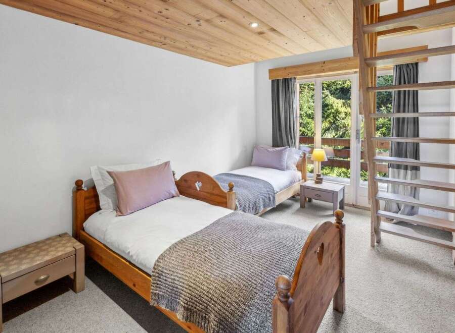 This charming bedroom features two cozy beds with wooden frames, perfect for a comfortable stay.