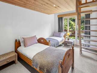 This charming bedroom features two cozy beds with wooden frames, perfect for a comfortable stay.