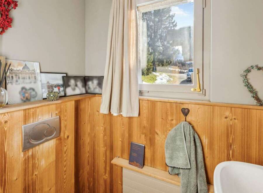 This charming bathroom features a warm, inviting ambiance with its wooden paneling and natural light.