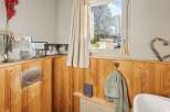 This charming bathroom features a warm, inviting ambiance with its wooden paneling and natural light.