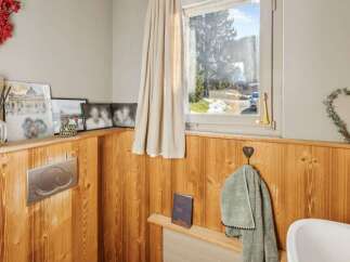 This charming bathroom features a warm, inviting ambiance with its wooden paneling and natural light.