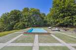 Enjoy luxurious outdoor living with this stunning property featuring a pristine swimming pool surrounded by lush greenery.