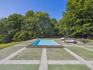 Enjoy luxurious outdoor living with this stunning property featuring a pristine swimming pool surrounded by lush greenery.