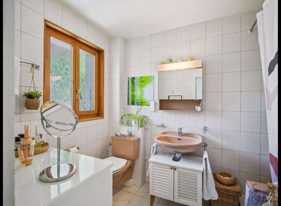 This charming bathroom features a warm, inviting atmosphere with its natural light and neutral color palette.
