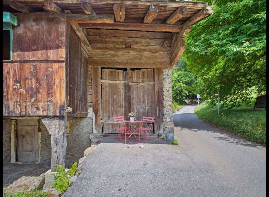 Discover the charm of this unique property, featuring a rustic wooden facade and a welcoming outdoor seating area.