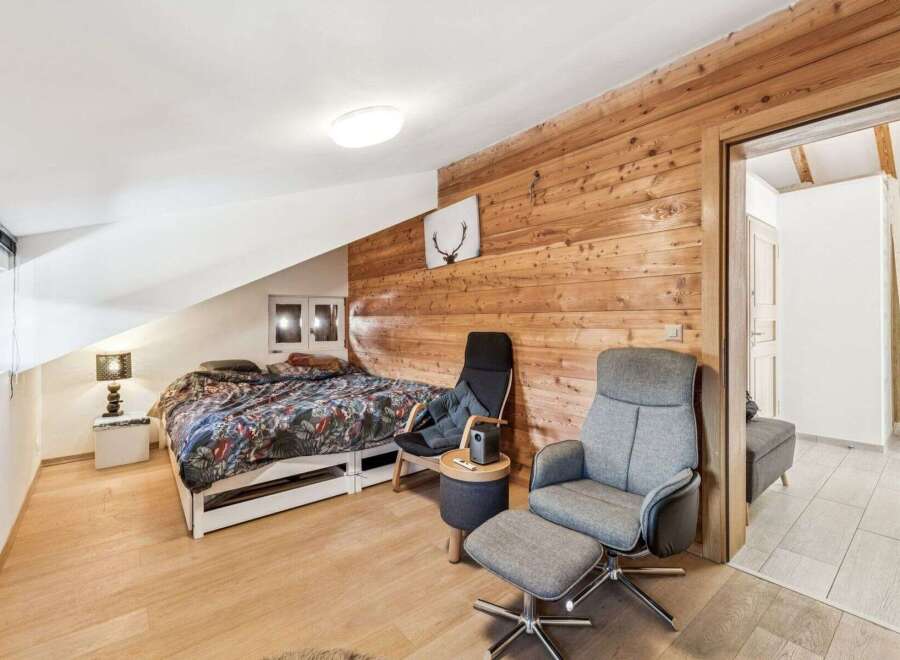 Discover the charm of this cozy bedroom featuring a unique wooden accent wall and a comfortable seating area.