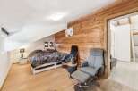 Discover the charm of this cozy bedroom featuring a unique wooden accent wall and a comfortable seating area.