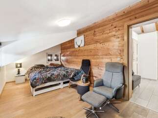 Discover the charm of this cozy bedroom featuring a unique wooden accent wall and a comfortable seating area.
