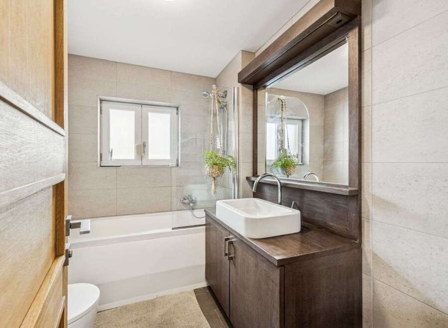 This modern bathroom features a sleek design with a combination of wood and neutral tones.