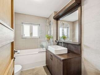 This modern bathroom features a sleek design with a combination of wood and neutral tones.