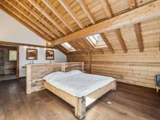 Experience rustic elegance in this stunning bedroom featuring exposed wooden beams and a cozy atmosphere.