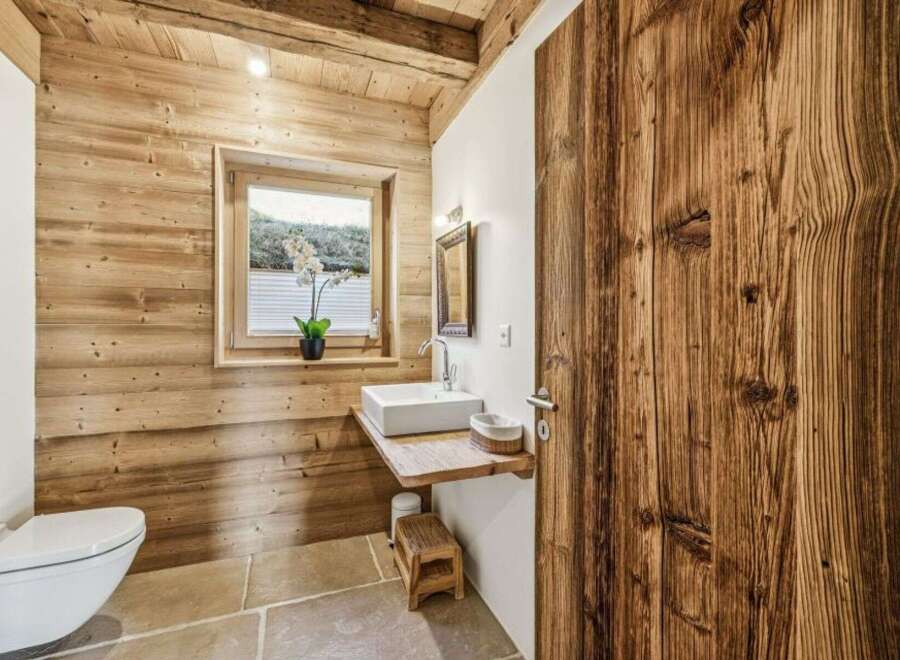 This stunning bathroom showcases rustic charm with its wooden walls and door, creating a warm and inviting atmosphere.