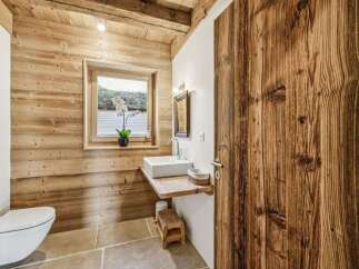 This stunning bathroom showcases rustic charm with its wooden walls and door, creating a warm and inviting atmosphere.