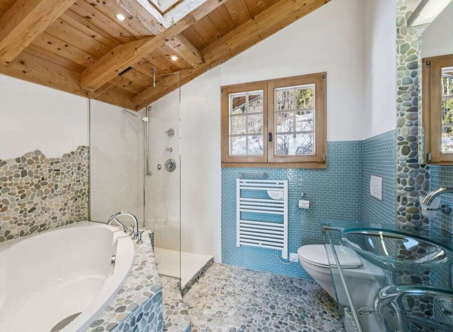 Experience luxury in this stunning bathroom featuring a unique pebble stone design and a modern glass shower.