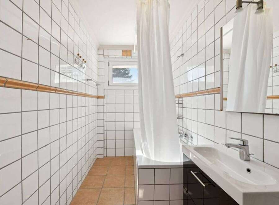 This bathroom features a clean and modern design with white tiled walls and a sleek vanity.