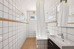 This bathroom features a clean and modern design with white tiled walls and a sleek vanity.