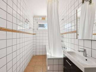 This bathroom features a clean and modern design with white tiled walls and a sleek vanity.