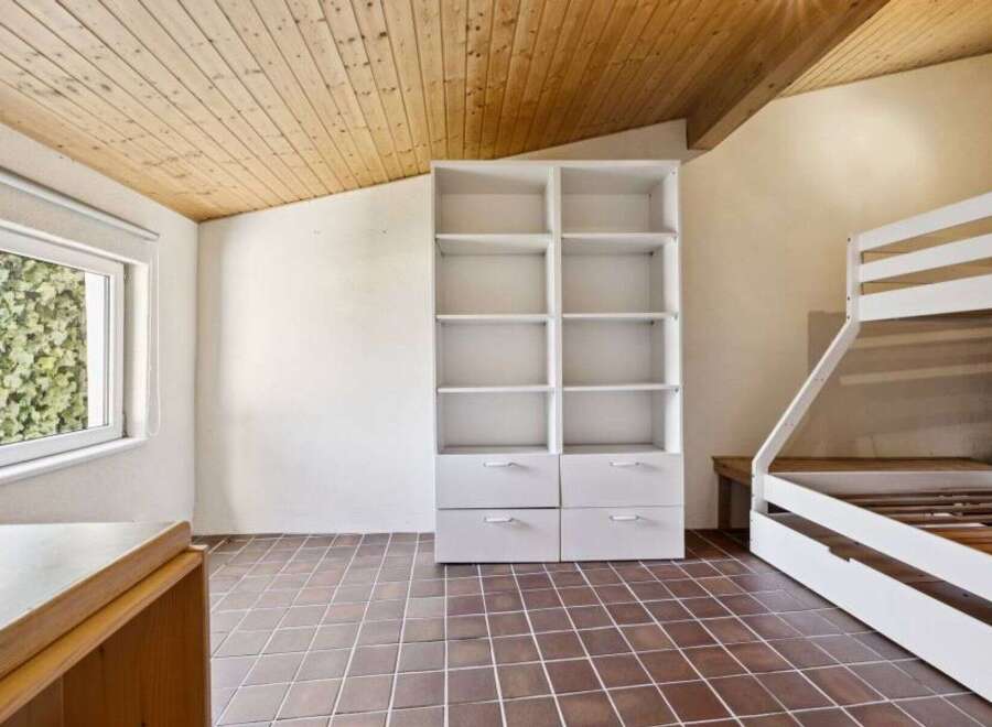 This charming room features a unique wooden ceiling and tiled flooring, creating a warm and inviting atmosphere.