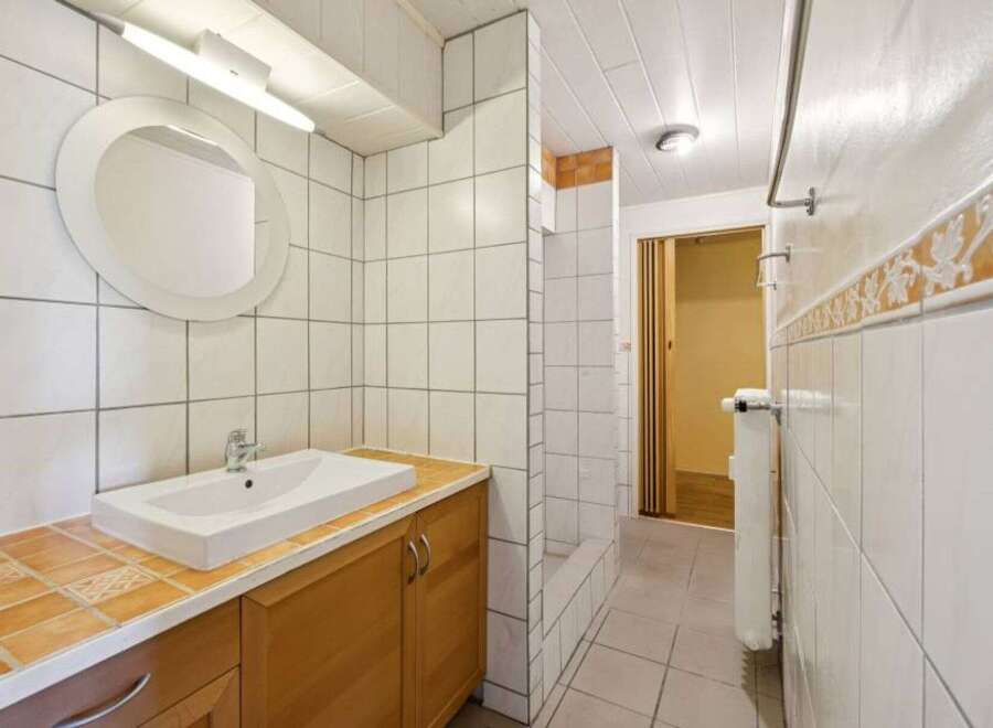 This bathroom features a clean and modern design with white tiles and a sleek sink.
