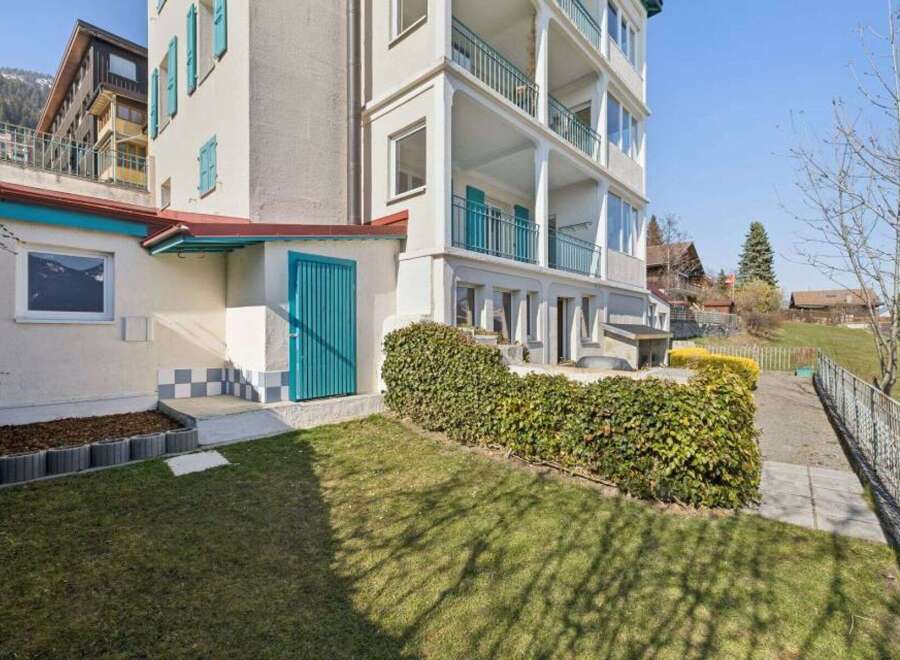 Discover this charming property featuring a multi-story building with balconies and a lush green lawn.