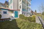 Discover this charming property featuring a multi-story building with balconies and a lush green lawn.