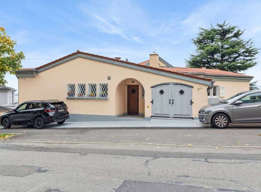 Charming single-family home featuring a welcoming arched entryway and a detached garage with elegant double doors.
