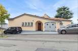 Charming single-family home featuring a welcoming arched entryway and a detached garage with elegant double doors.