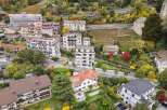 This aerial view showcases a charming European village nestled on a hillside, with a mix of modern and traditional architecture.