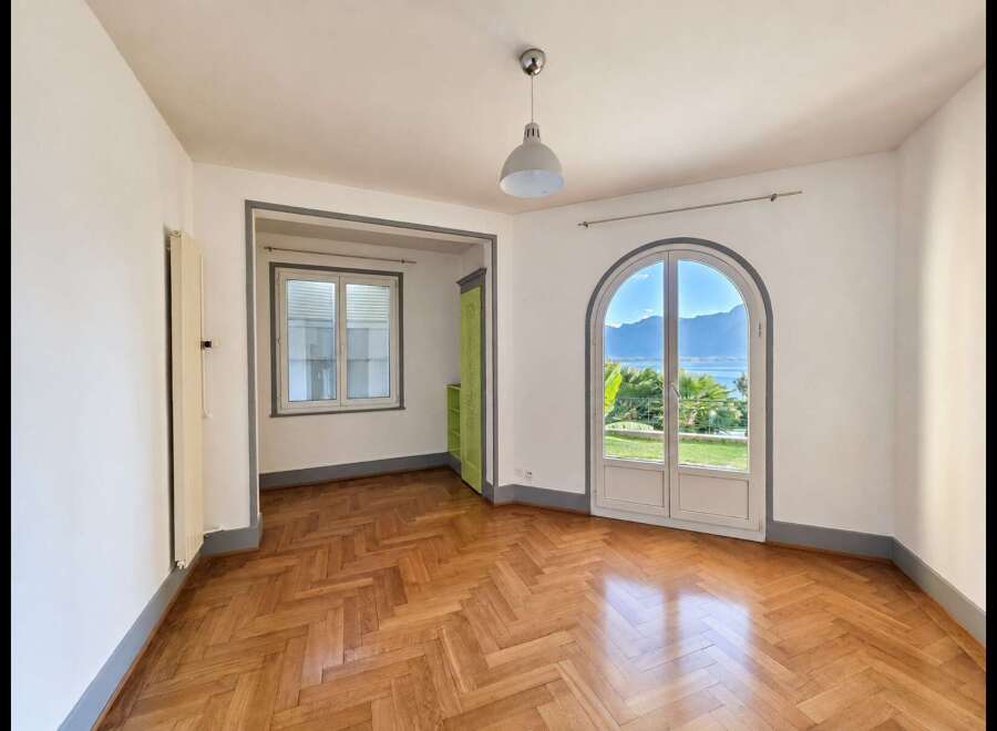 Experience breathtaking lake and mountain views from this stunning room, featuring a charming arched doorway that opens to the outdoors.
