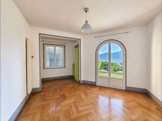 Experience breathtaking lake and mountain views from this stunning room, featuring a charming arched doorway that opens to the outdoors.