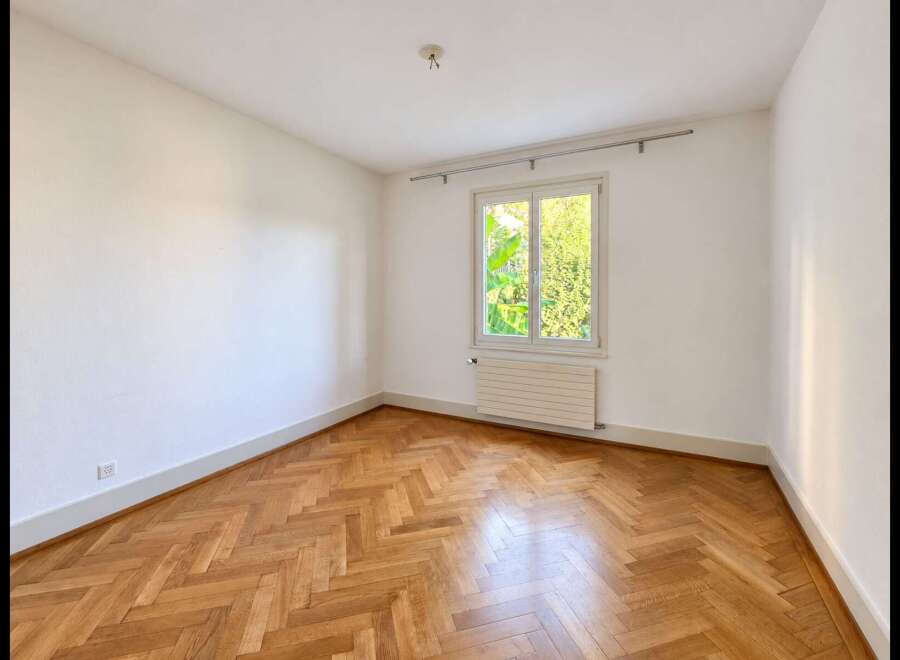 This unfurnished room features a beautiful herringbone hardwood floor that adds warmth and character.