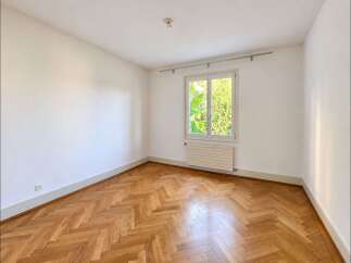 This unfurnished room features a beautiful herringbone hardwood floor that adds warmth and character.