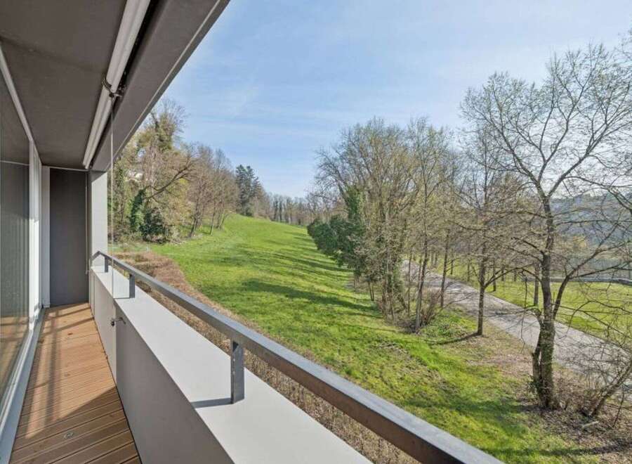 Enjoy breathtaking views from this stunning property! This home features a spacious balcony overlooking a lush green landscape and mature trees.