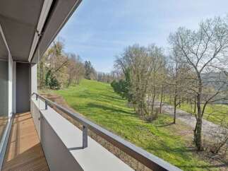 Enjoy breathtaking views from this stunning property! This home features a spacious balcony overlooking a lush green landscape and mature trees.