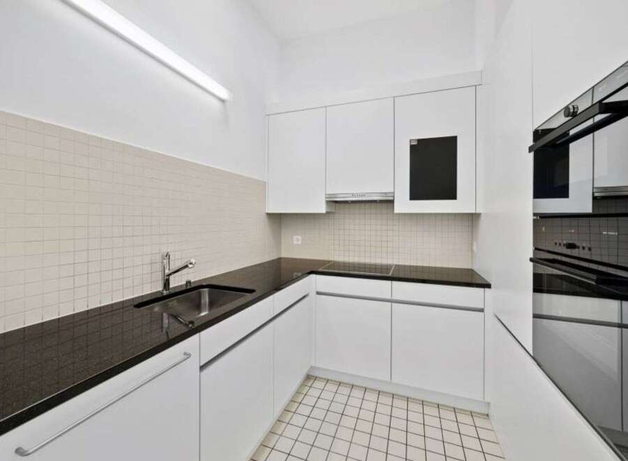 Modern kitchen with sleek white cabinetry and a dark countertop.