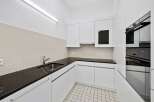Modern kitchen with sleek white cabinetry and a dark countertop.