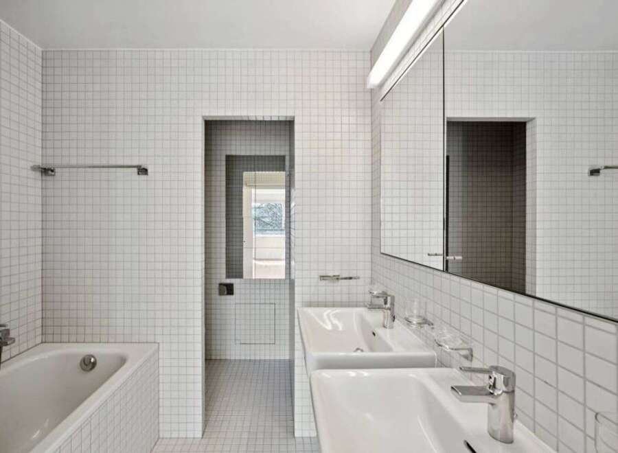 This modern bathroom features a sleek design with white tiled walls and floors, creating a bright and spacious feel.