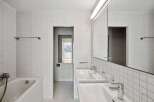 This modern bathroom features a sleek design with white tiled walls and floors, creating a bright and spacious feel.