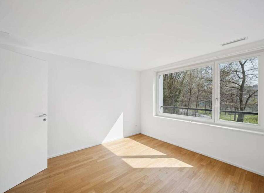This bright and airy room features a large window that offers stunning views of the surrounding trees.