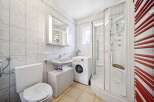 This well-maintained bathroom features a modern design with a washing machine, a shower, and a toilet.