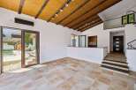 Experience modern living in this spacious room featuring a vaulted wooden ceiling with exposed beams and track lighting.