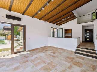 Experience modern living in this spacious room featuring a vaulted wooden ceiling with exposed beams and track lighting.
