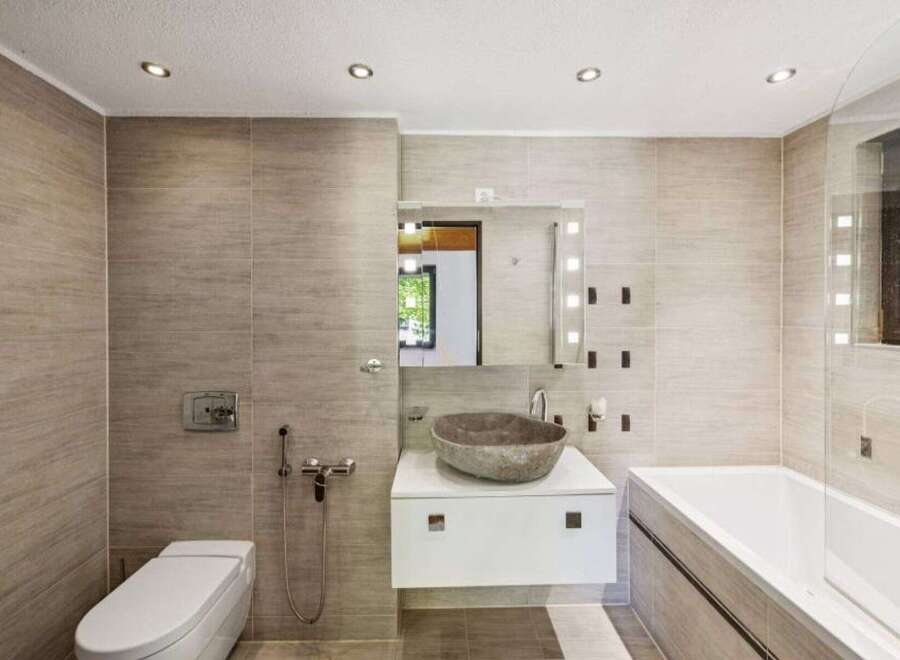 Experience modern luxury in this stunning bathroom featuring a sleek white vanity with a unique stone vessel sink.