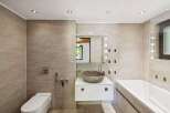Experience modern luxury in this stunning bathroom featuring a sleek white vanity with a unique stone vessel sink.