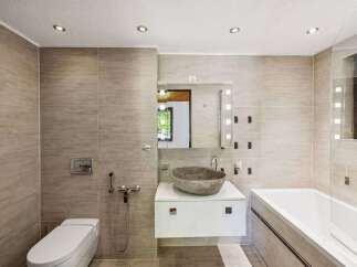 Experience modern luxury in this stunning bathroom featuring a sleek white vanity with a unique stone vessel sink.