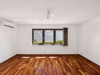 Experience breathtaking mountain views from this spacious room, featuring a beautiful hardwood floor and a large triple-pane window.