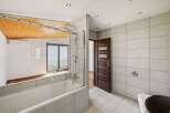 Experience modern comfort in this beautifully appointed bathroom, featuring a sleek bathtub with a glass enclosure and a rainfall showerhead.