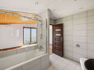 Experience modern comfort in this beautifully appointed bathroom, featuring a sleek bathtub with a glass enclosure and a rainfall showerhead.
