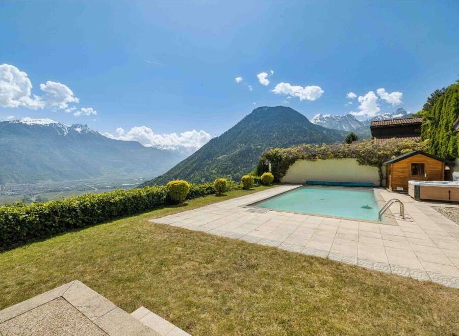 Experience luxury living with this stunning property featuring a pristine swimming pool and a relaxing hot tub, all set against a breathtaking mountain backdrop.