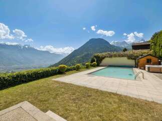 Experience luxury living with this stunning property featuring a pristine swimming pool and a relaxing hot tub, all set against a breathtaking mountain backdrop.